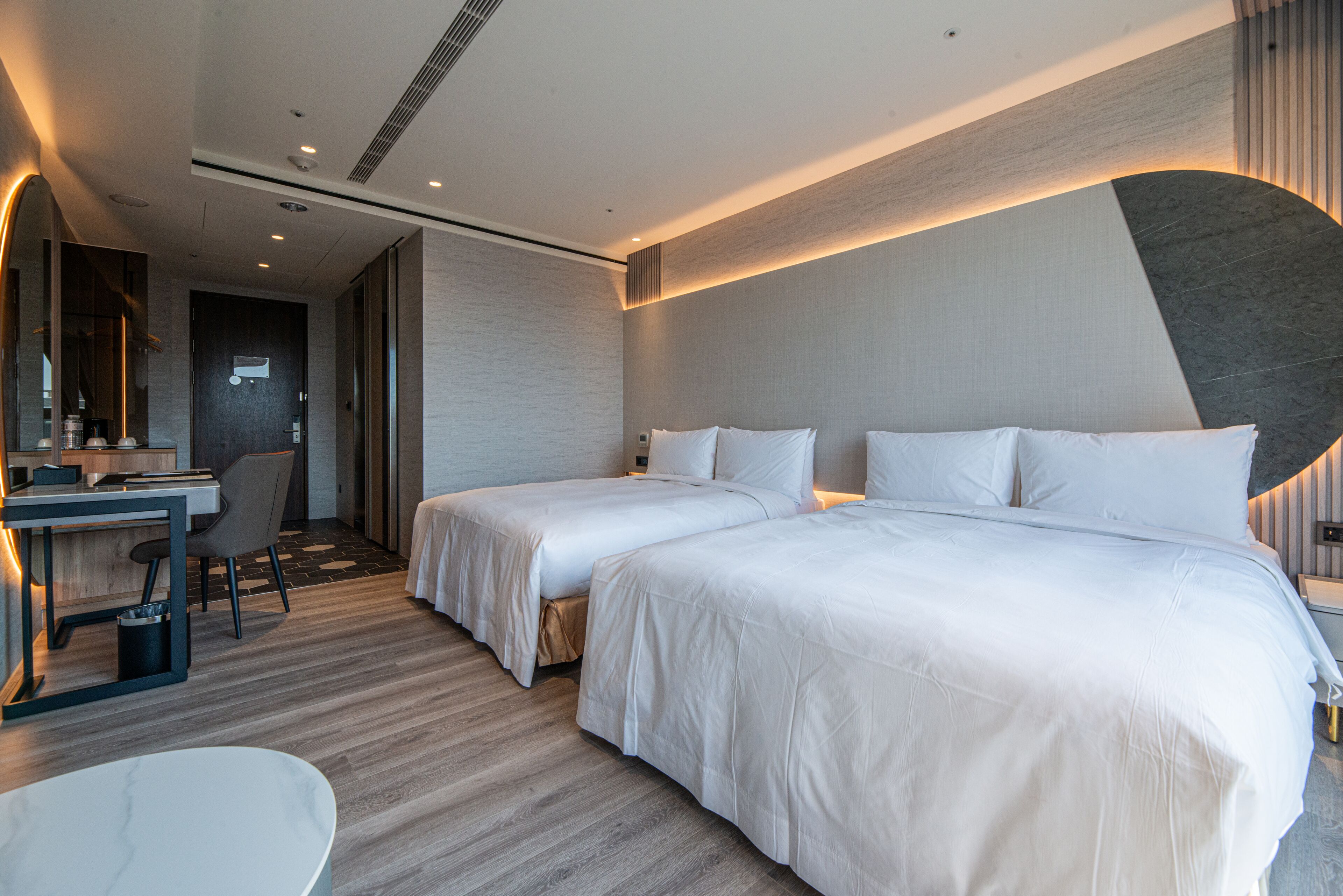 Une chambre d’hôtel moderne équipée de deux lits, d’un bureau et d’une chaise.