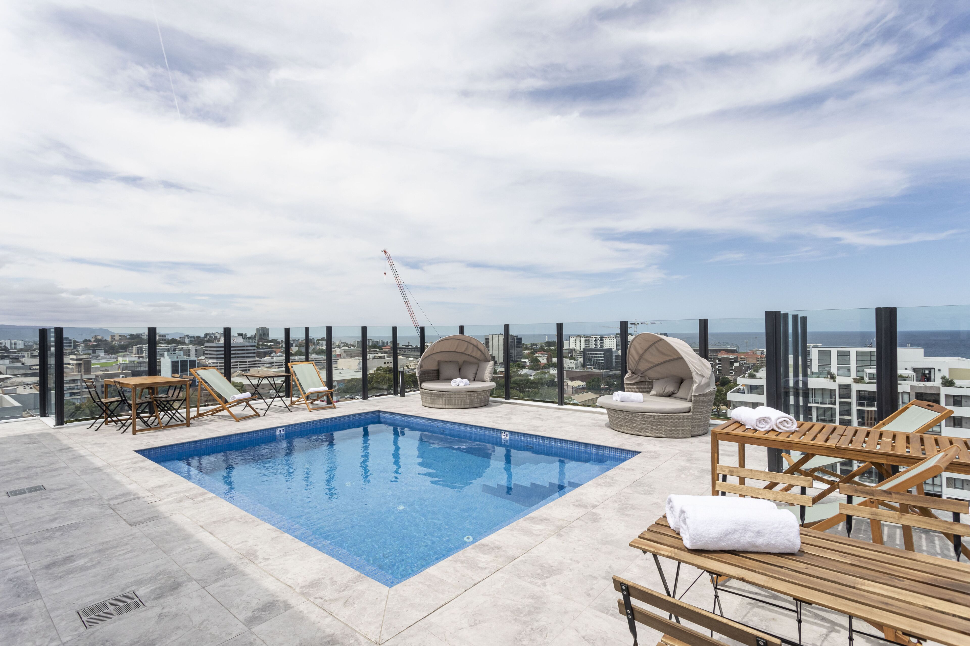 A rooftop pool with lounge chairs and a view of the city.