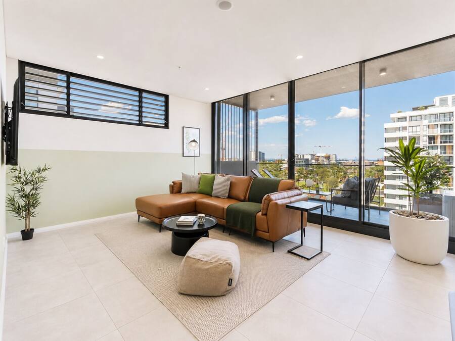 A modern living room with a sectional sofa, a coffee table, and a large window offering a city view.