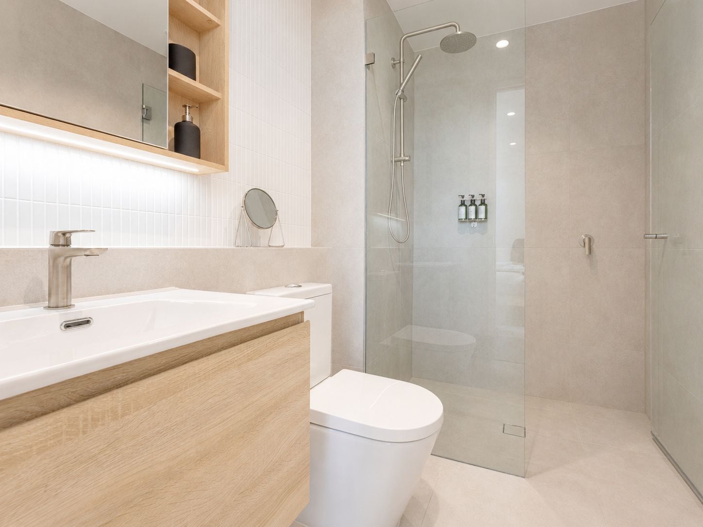 A modern bathroom with a glass-enclosed shower, a white sink, and a wooden vanity.