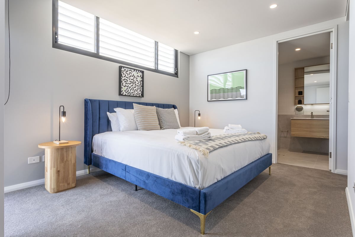 Un dormitorio moderno con una cama grande, mesitas de noche y un armario empotrado.