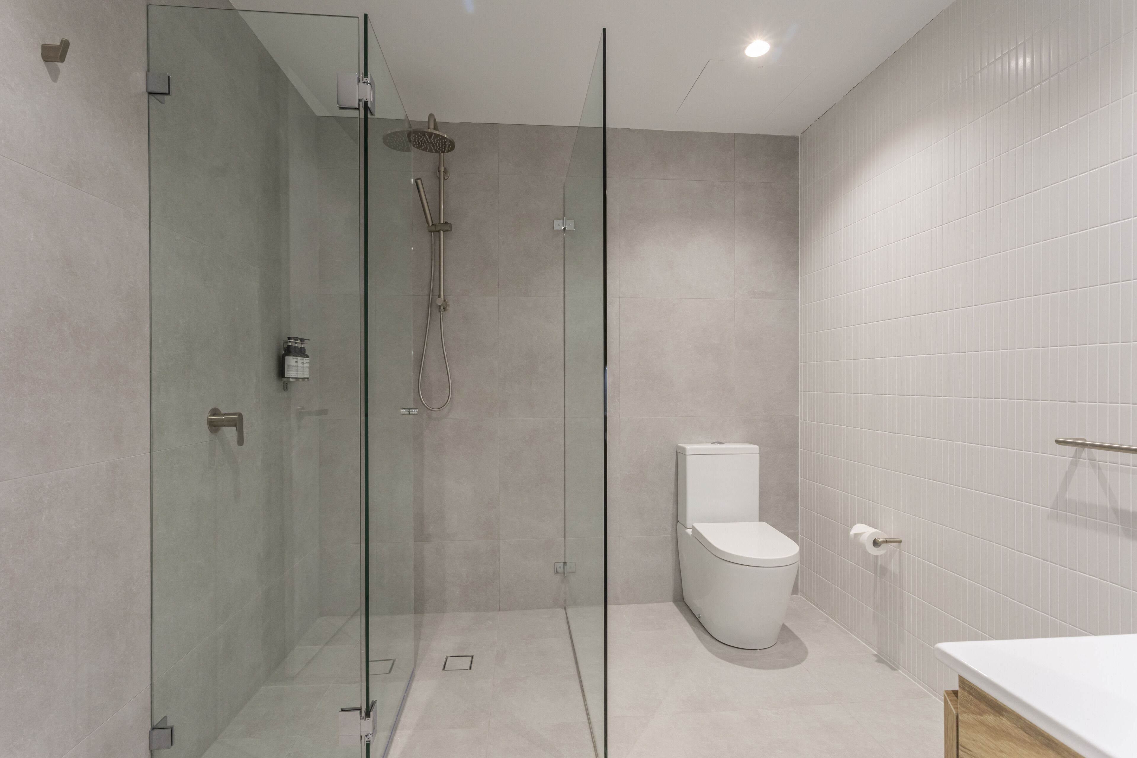 A modern bathroom with a glass-enclosed shower, a toilet, and a white sink.