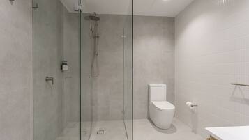 A modern bathroom with a glass-enclosed shower, a toilet, and a white sink.