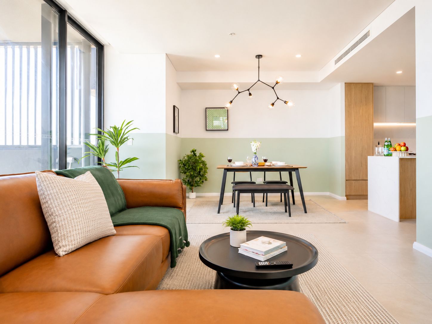 Una sala de estar moderna con un sofá de cuero, una mesa de centro redonda y un comedor con mesa y sillas.
