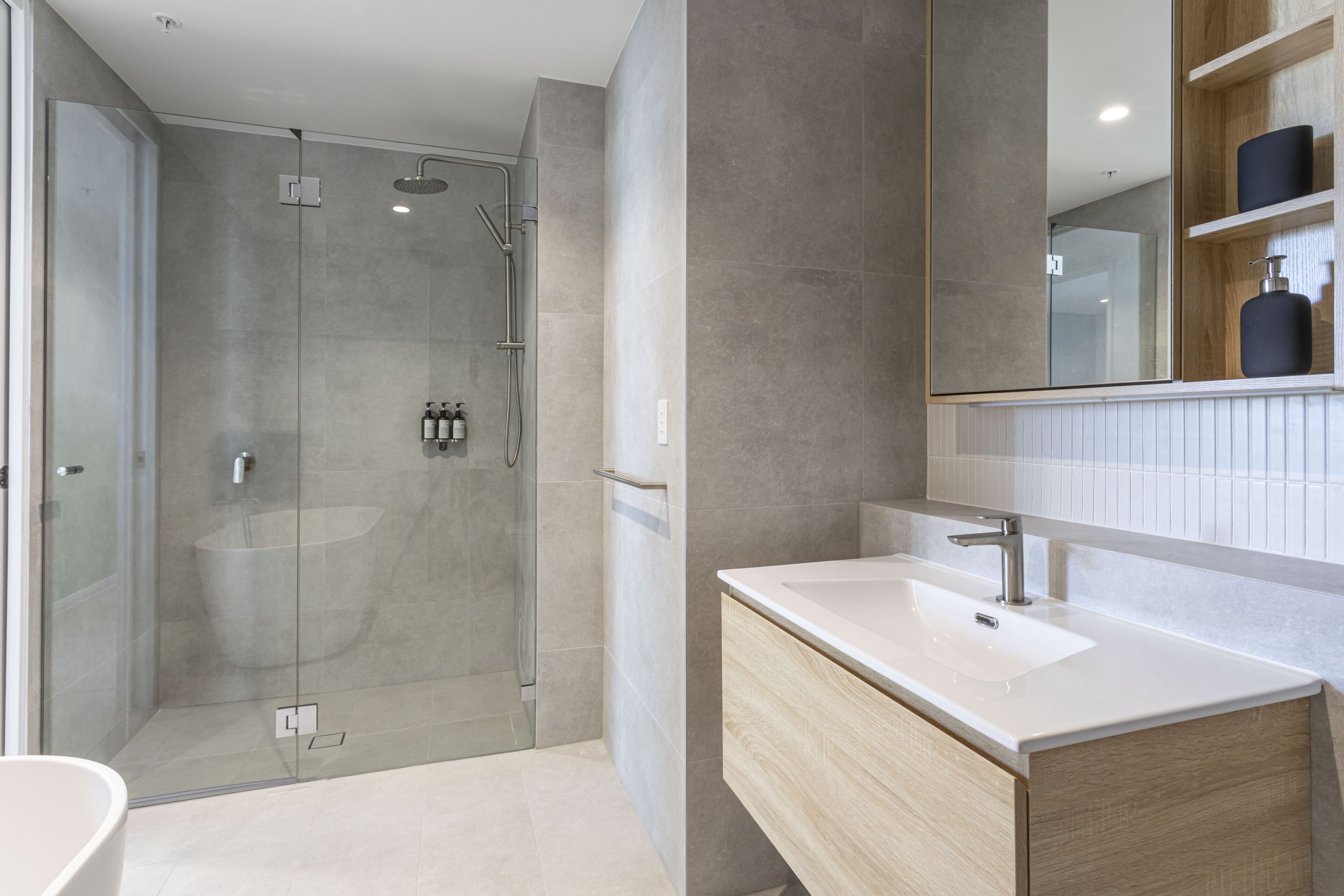 A modern bathroom with a glass-enclosed shower, a white sink, and a large mirror.