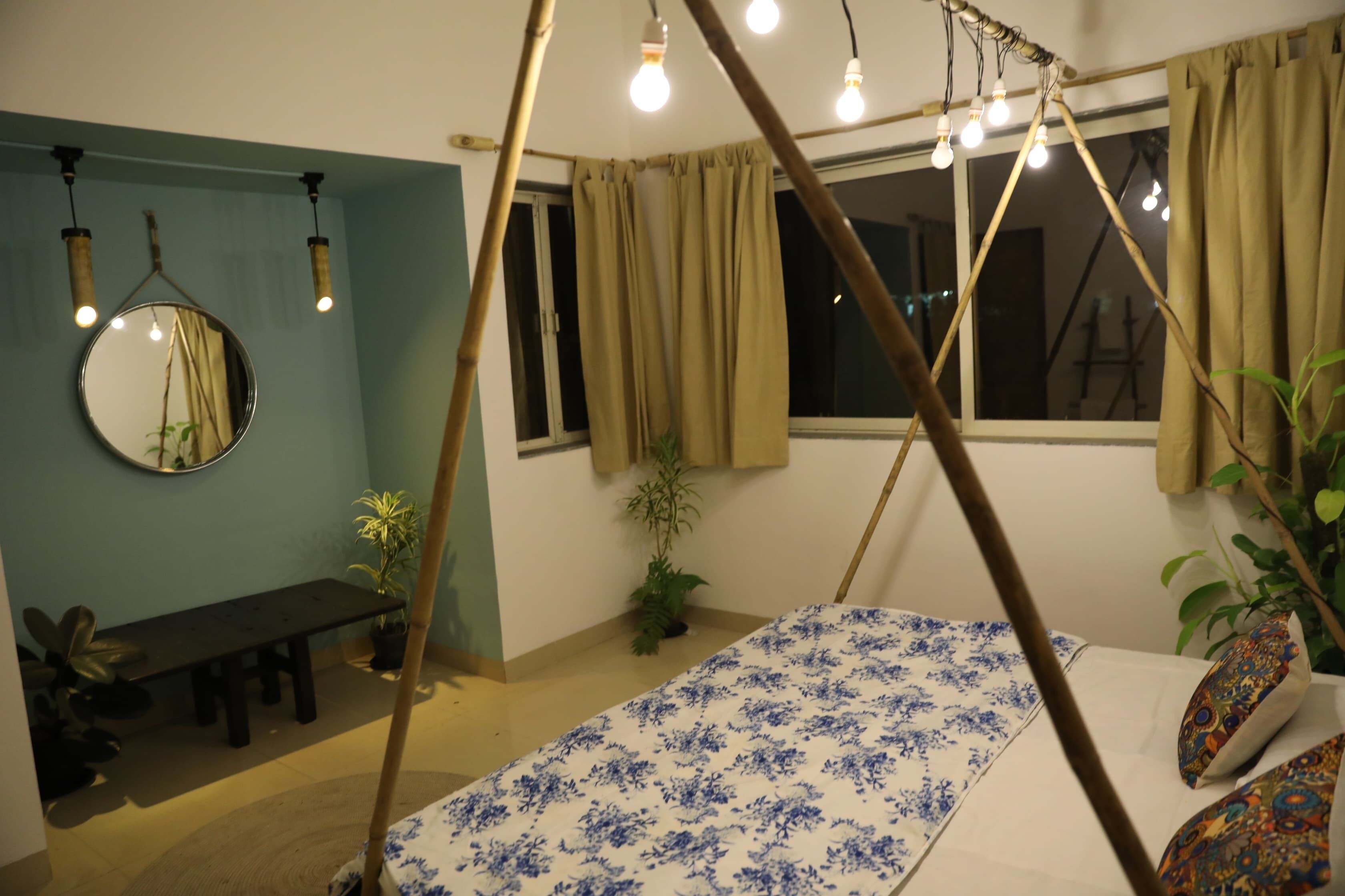 Une chambre à coucher avec un lit, un luminaire suspendu, une fenêtre avec des rideaux et un miroir au mur.