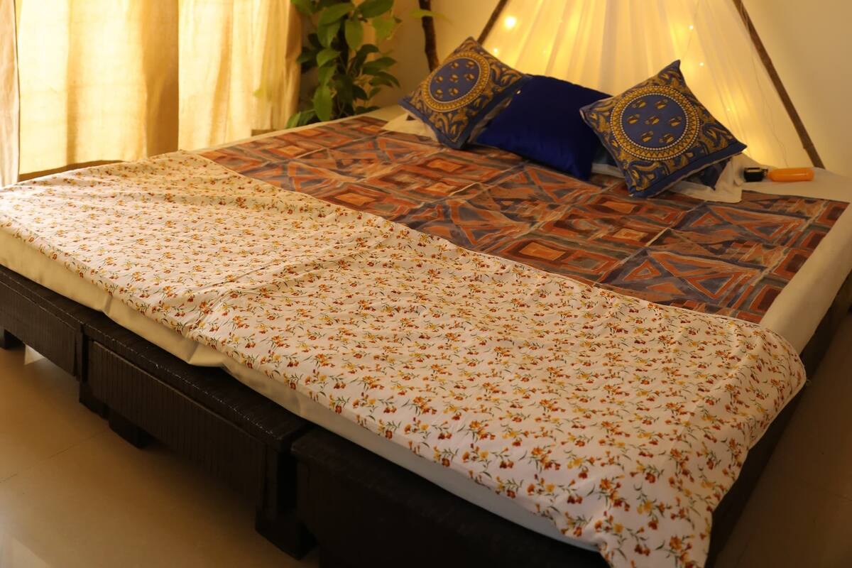 A bed with a floral bedspread, a bedside lamp, and decorative pillows.