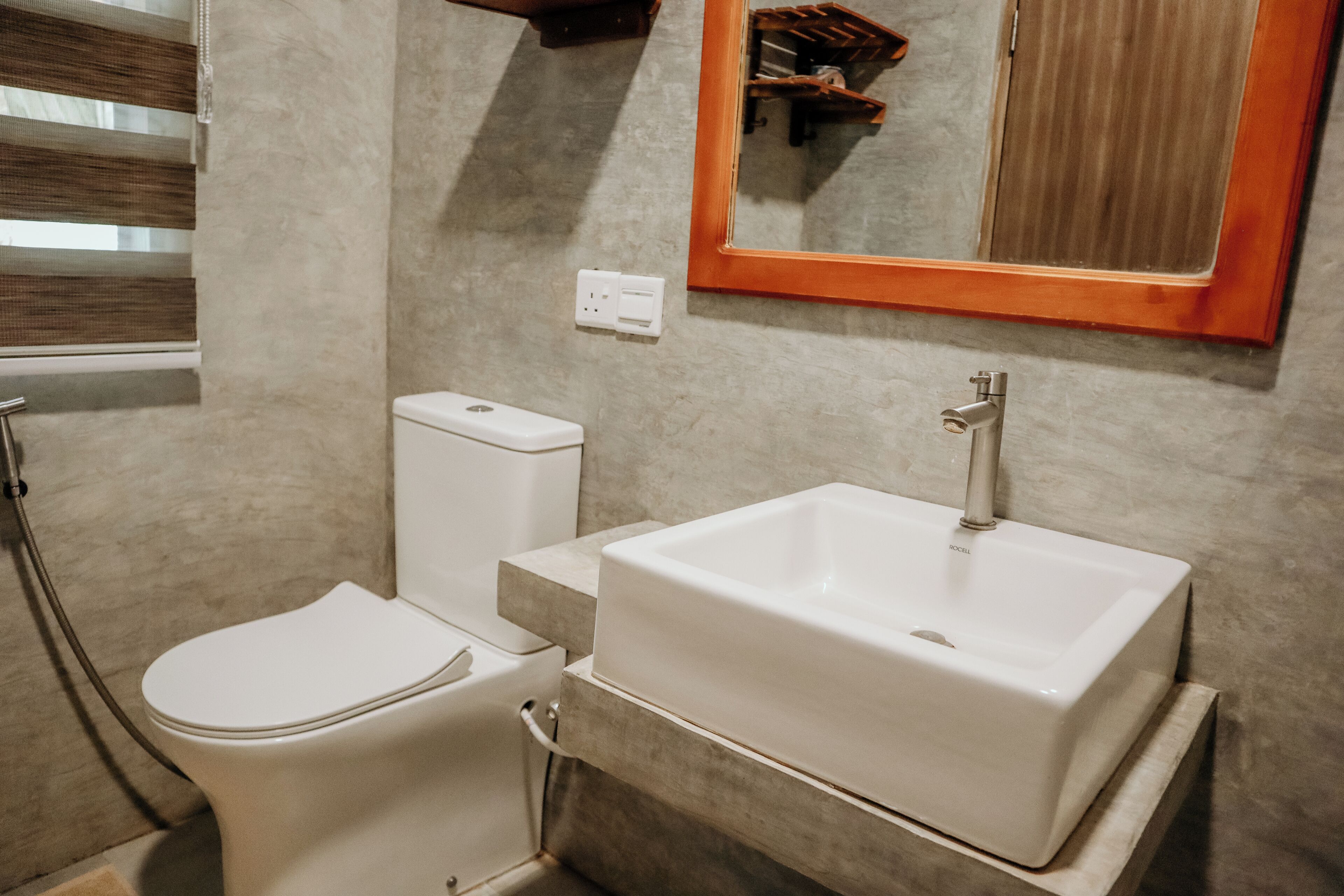 A bathroom with a toilet, sink, and mirror.