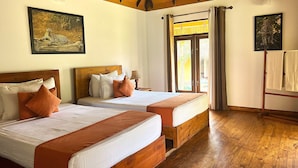 Une chambre d’hôtel avec deux lits, un plancher en bois et une grande fenêtre avec des rideaux.