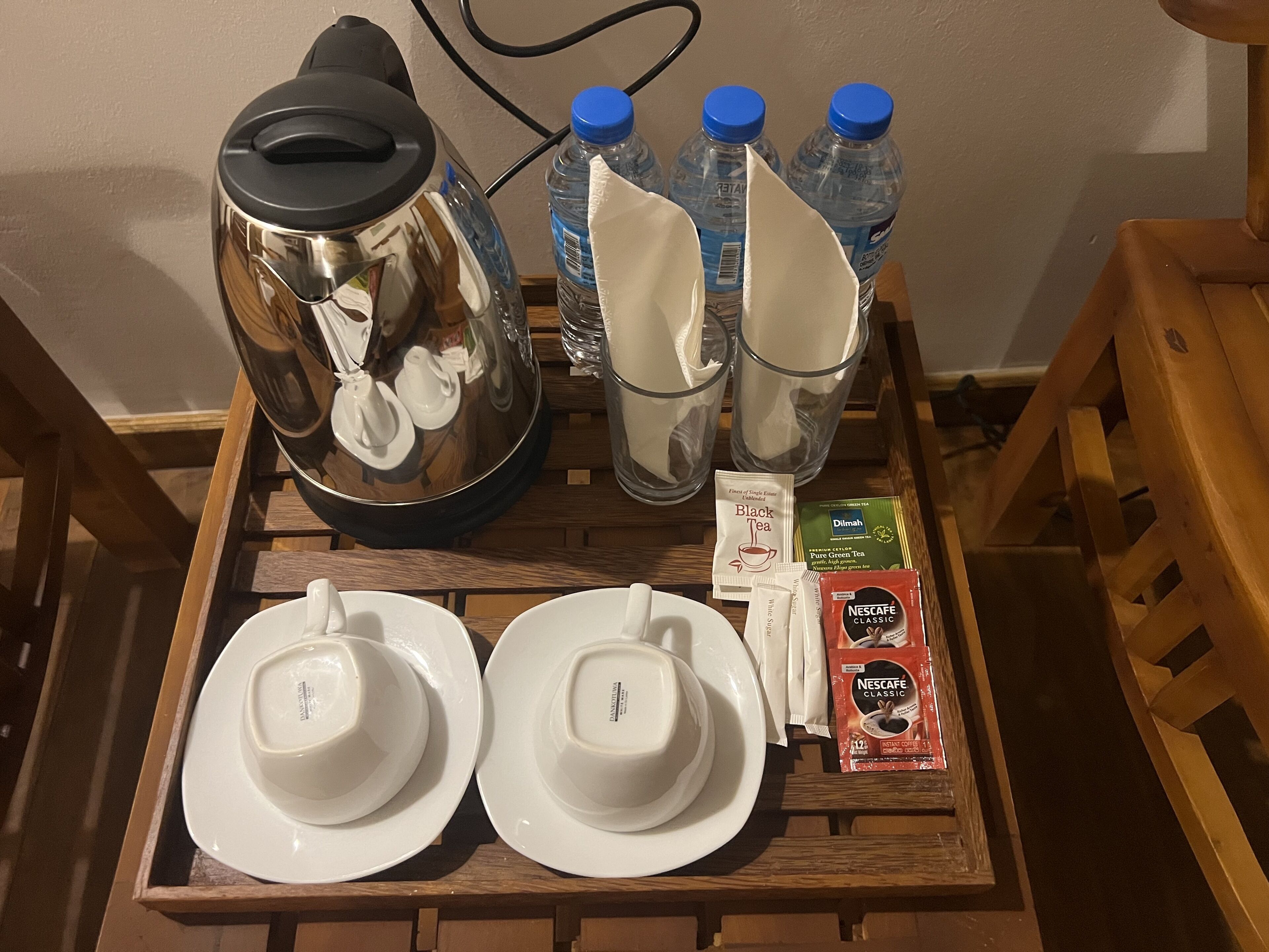 A tray with a kettle, water bottles, cups, and tea packets.