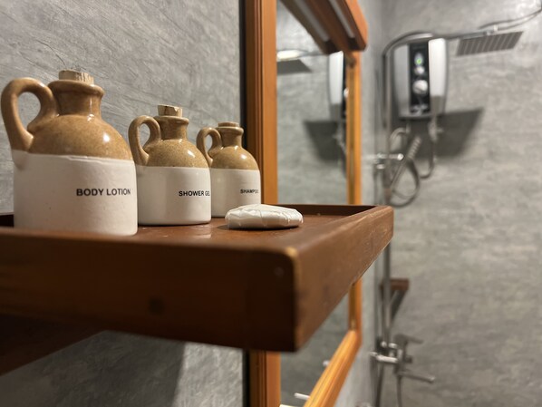 A bathroom shelf with three toiletry containers labeled "BODY LOTION," "SHOWER GEL," and "SHAMPOO."