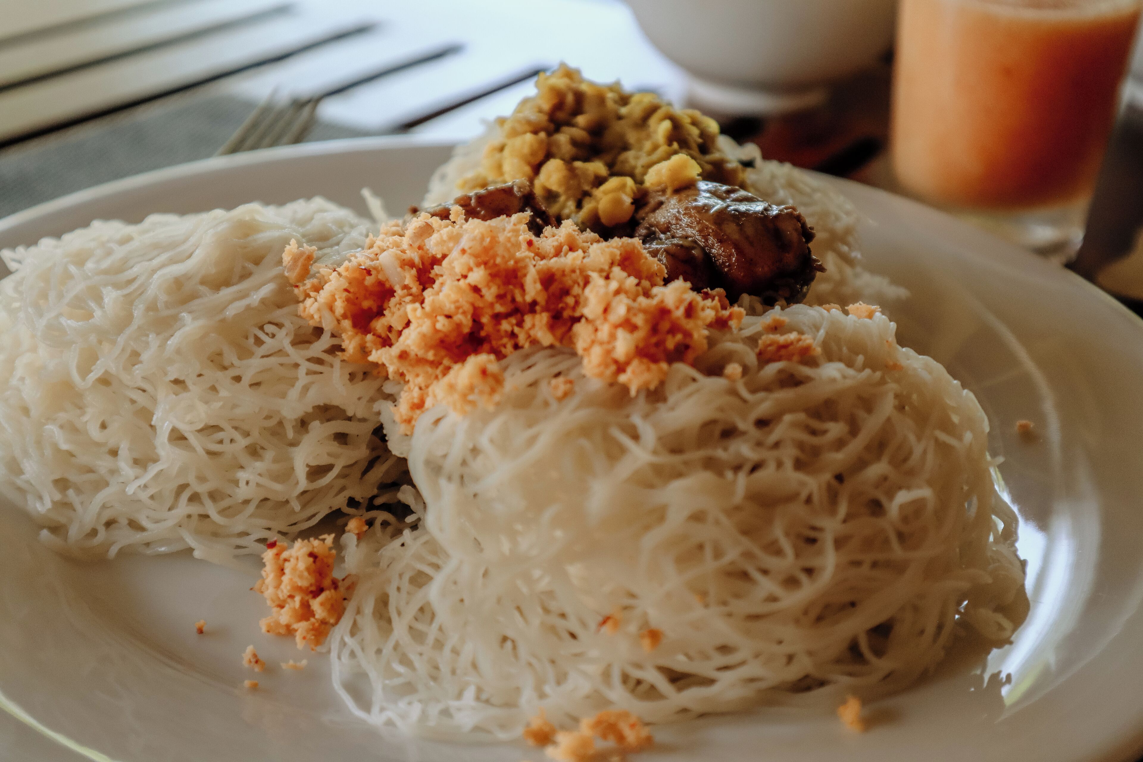 A plate of white noodles with a topping of minced meat and peanuts.