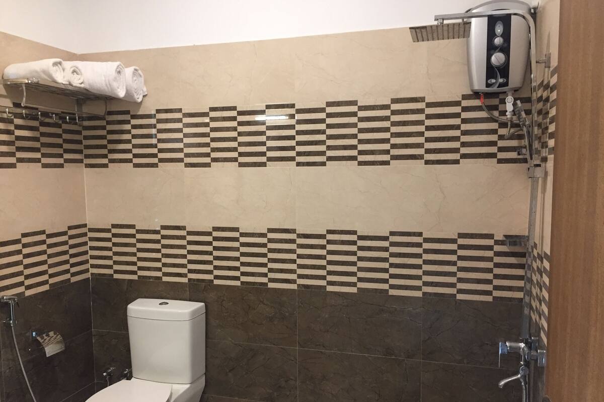 Une salle de bain équipée de toilettes, d’une douche et d’un porte-serviettes.