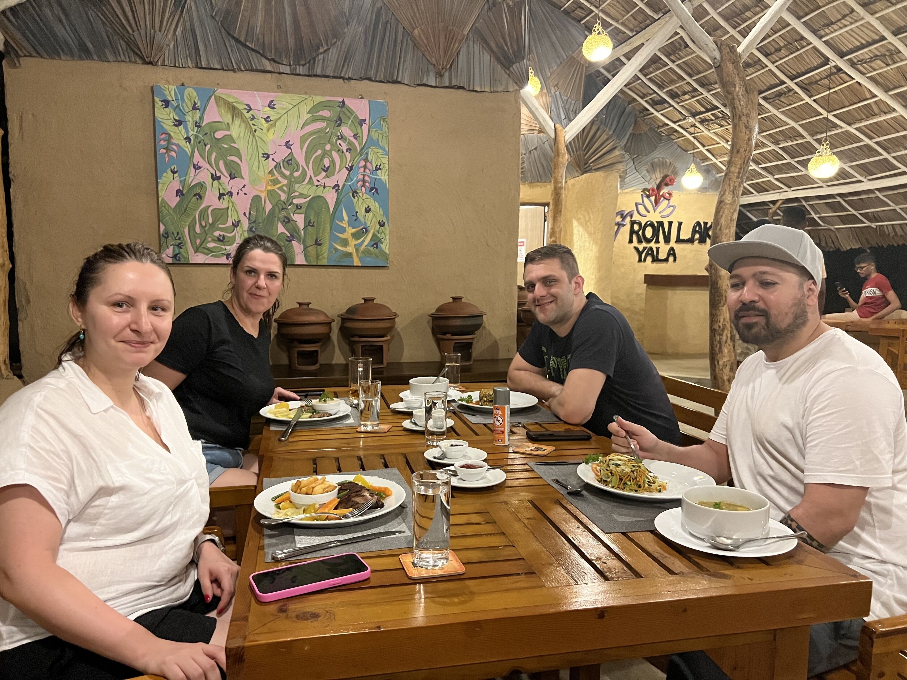 A group of people dining at a wooden table with various dishes and drinks.