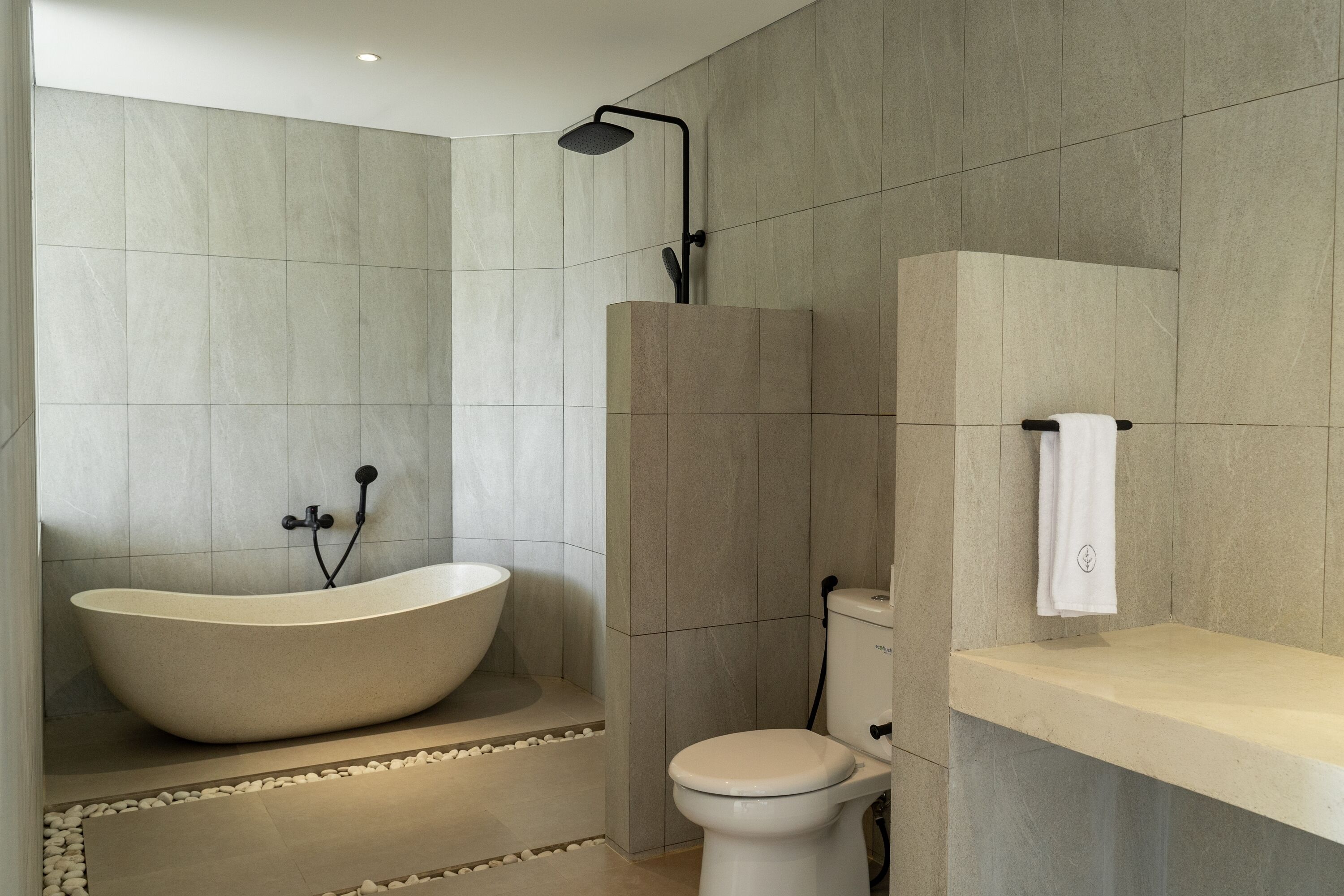 A modern bathroom with a freestanding bathtub, a toilet, and a shower area.