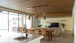 A modern kitchen with a dining area, large windows, and a flat-screen TV. -  JadenHill CityView 8BR Villa Heated Pool+Movieroom (Cimenyan)