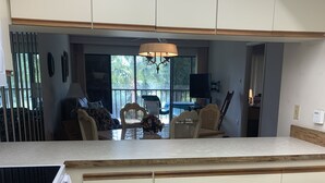 A modern kitchen with a central island, wooden cabinets, and a view to a patio area. - Near Beaches! UPDATED! Peaceful Forest Park Condo 2 bd 2 bth. Heat comm pool (Englewood)