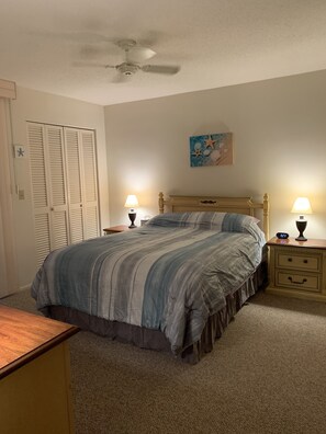 A bedroom with a bed, two bedside tables with lamps, a ceiling fan, a closet with louvered doors, and a wall-mounted picture. - Near Beaches! UPDATED! Peaceful Forest Park Condo 2 bd 2 bth. Heat comm pool (Englewood)