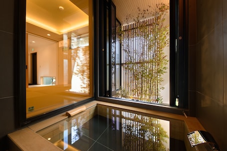 A modern hotel lobby with a glass floor, a reception desk, and a view of a bamboo garden.