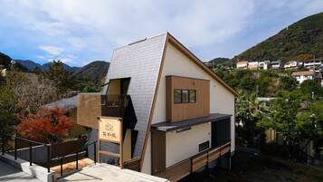 A modern building with a sloped roof, a wooden deck, and a small window.
