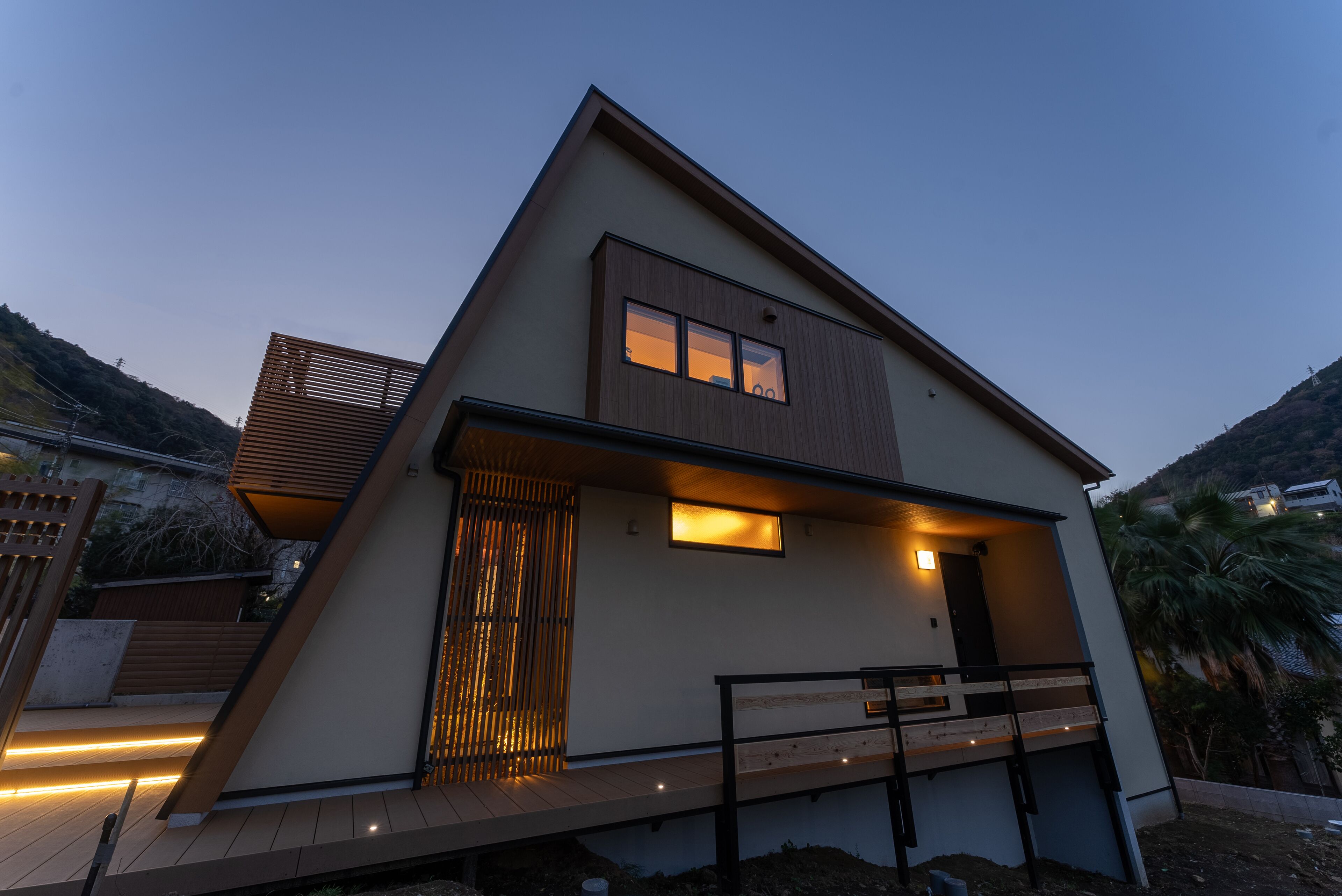 A modern two-story house with a flat roof, large windows, and a balcony.