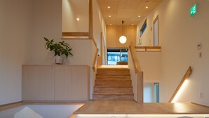 Una hall d'albergo moderna con una scala in legno, una reception e una pianta in vaso.