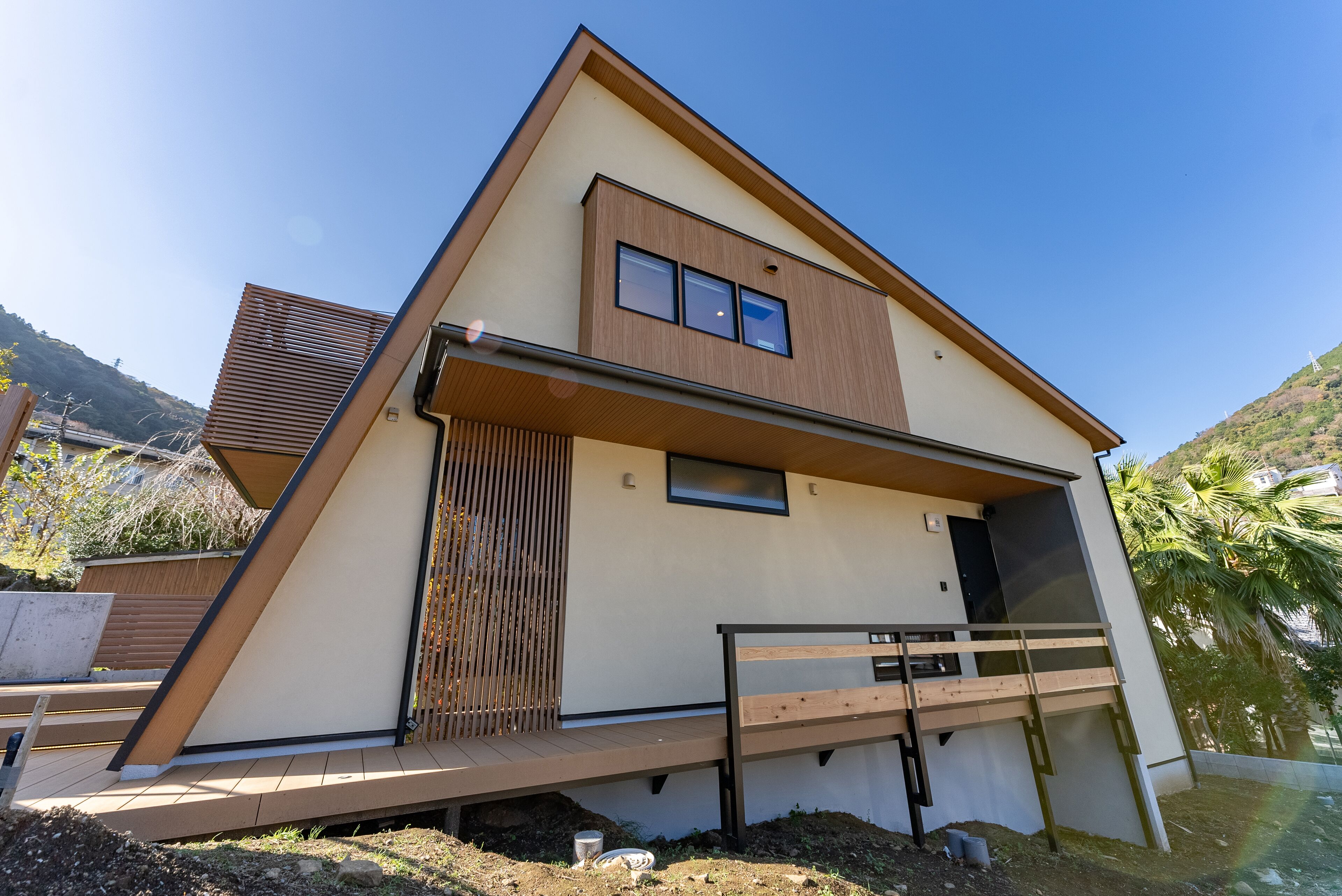 A modern house with a sloped roof, a balcony, and a small deck area.