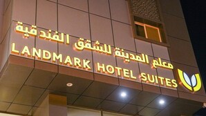 Un cartel de hotel con texto en árabe e inglés que indica que es el Landmark Hotel Suites.