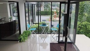 Un moderno vestíbulo de hotel con entrada de puerta de cristal, un mostrador de recepción y un pequeño espacio de descanso con una mesa y sillas.