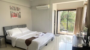 Habitación de hotel con cama, escritorio, silla, ventana con vistas a zonas verdes y un equipo de aire acondicionado.