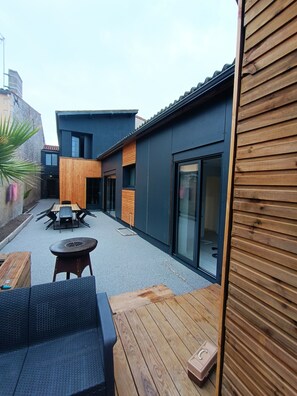 Eine moderne Terrassengestaltung mit Holzmöbeln und einer Glastür zum Gebäude.