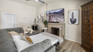 A modern living room with a large flat-screen TV, a fireplace, and artwork on the walls. - Kristys Kastle (Phoenix)
