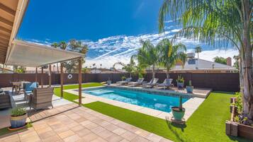 A backyard with a swimming pool, patio furniture, and a pergola.