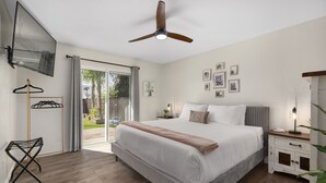 A bedroom with a large bed, a ceiling fan, a TV mounted on the wall, and a sliding glass door leading to a balcony. - Kristys Kastle (Phoenix)