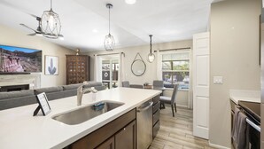 A modern kitchen with a large island, stainless steel appliances, and pendant lighting. - Kristys Kastle (Phoenix)