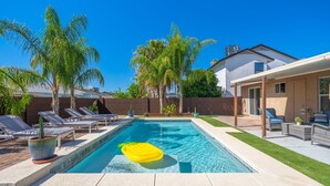 A rectangular swimming pool with a yellow float, surrounded by lounge chairs and palm trees. - Kristys Kastle (Phoenix)