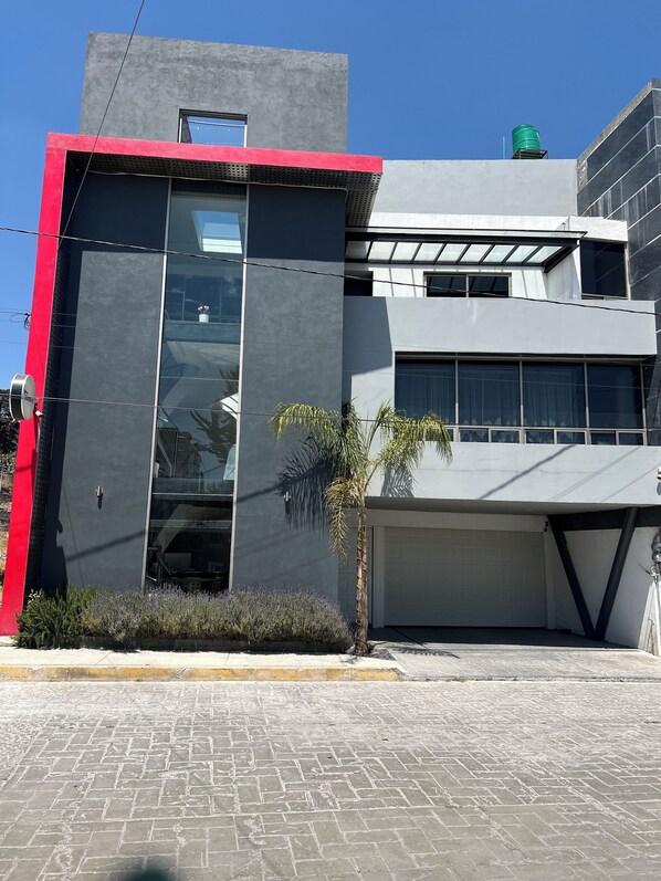 Un edificio moderno con fachada roja y gris, ventanas grandes y un garaje.