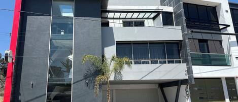 Un edificio moderno con garaje, ventanas amplias y una palmera pequeña.