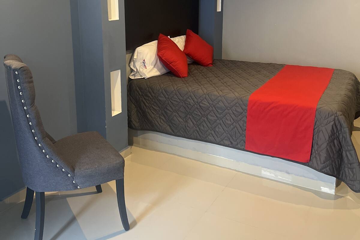 A bedroom with a bed, a chair, and a nightstand.