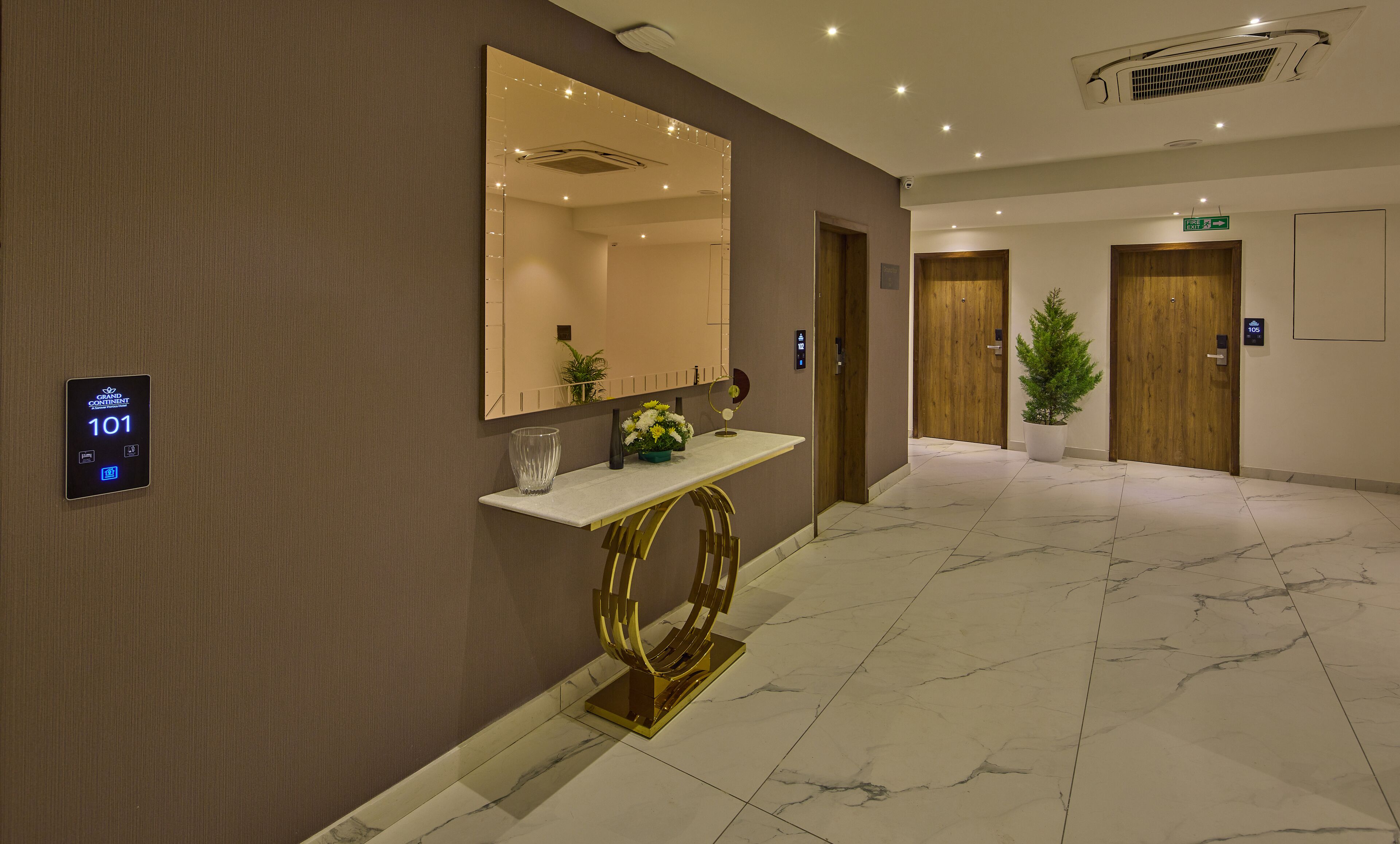 A modern hotel lobby with a marble floor, a reception desk, a large mirror, and a digital display showing room number 101.