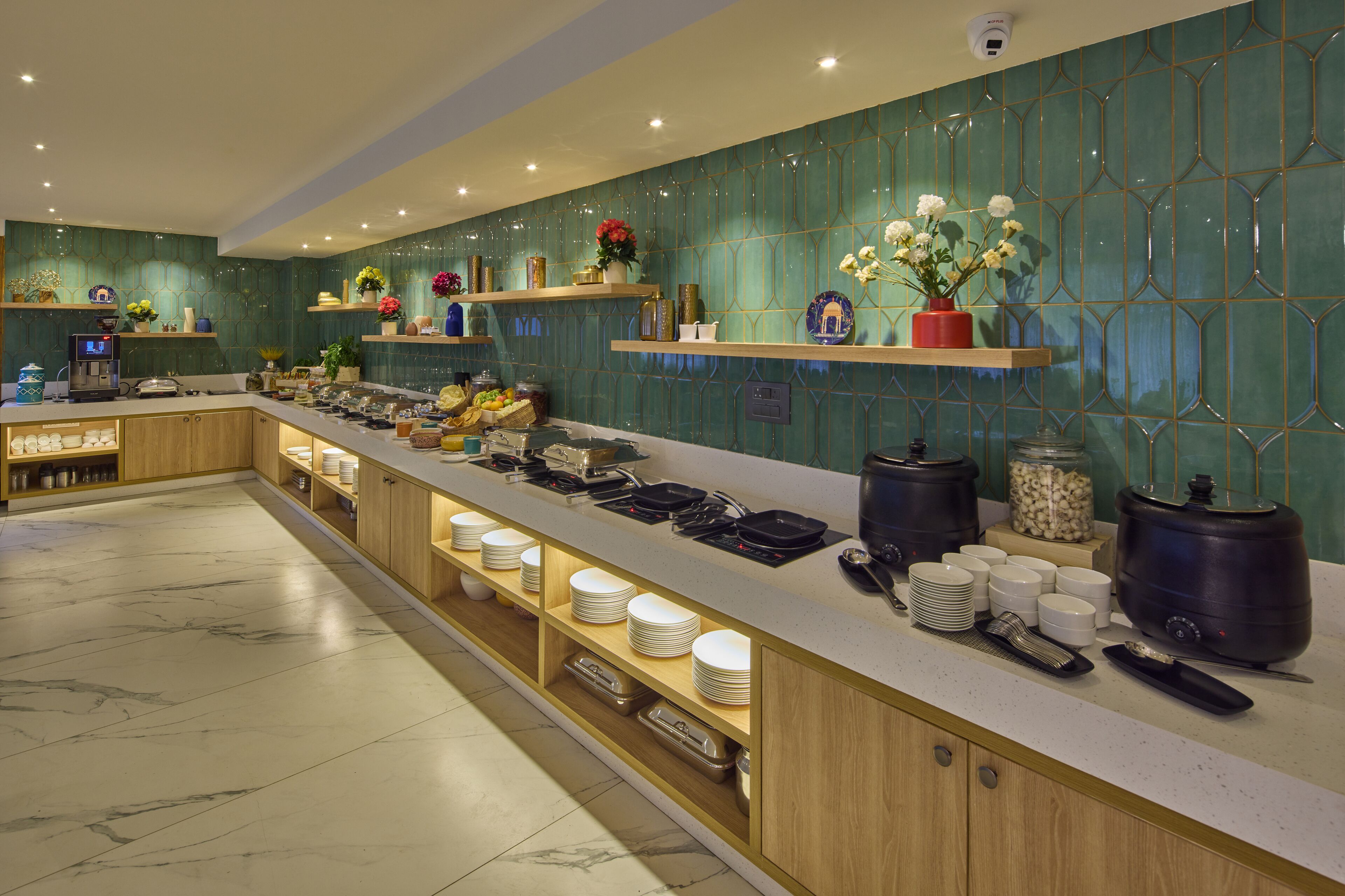 A buffet setup with a marble floor, wooden cabinets, and a teal backsplash.