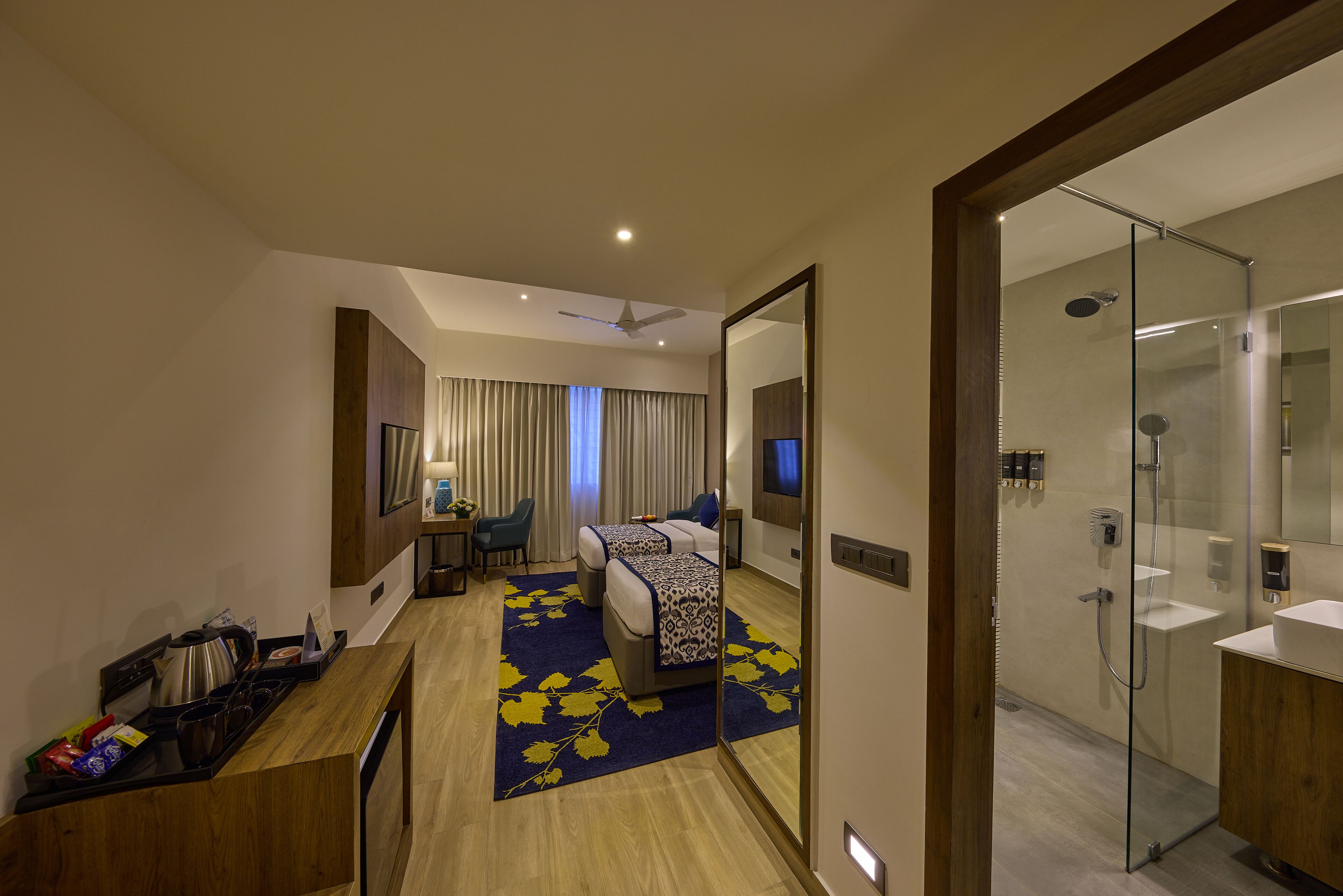 A hotel room with a bed, a desk, a shower, and a bathroom.