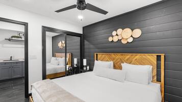 Um quarto moderno com uma cama grande, um ventilador de teto, cabeceira de madeira e um espelho fixado na parede.
