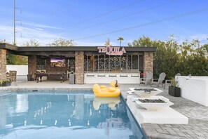A pool area with a floating pool chair, a bar with a sign reading "TEQUILA", and outdoor seating.