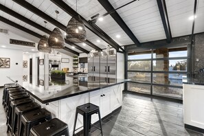Une cuisine moderne dotée d’un grand îlot central, d’appareils électroménagers en acier inoxydable et d’une enseigne de style rustique.