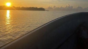 A boat's interior with a view of a sunset over water.