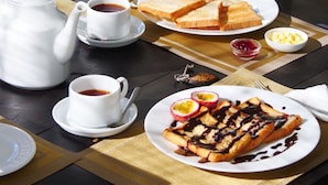 A table set with a teapot, cups, plates of toast, and a dessert. - Cozy Cocos (Weligama)