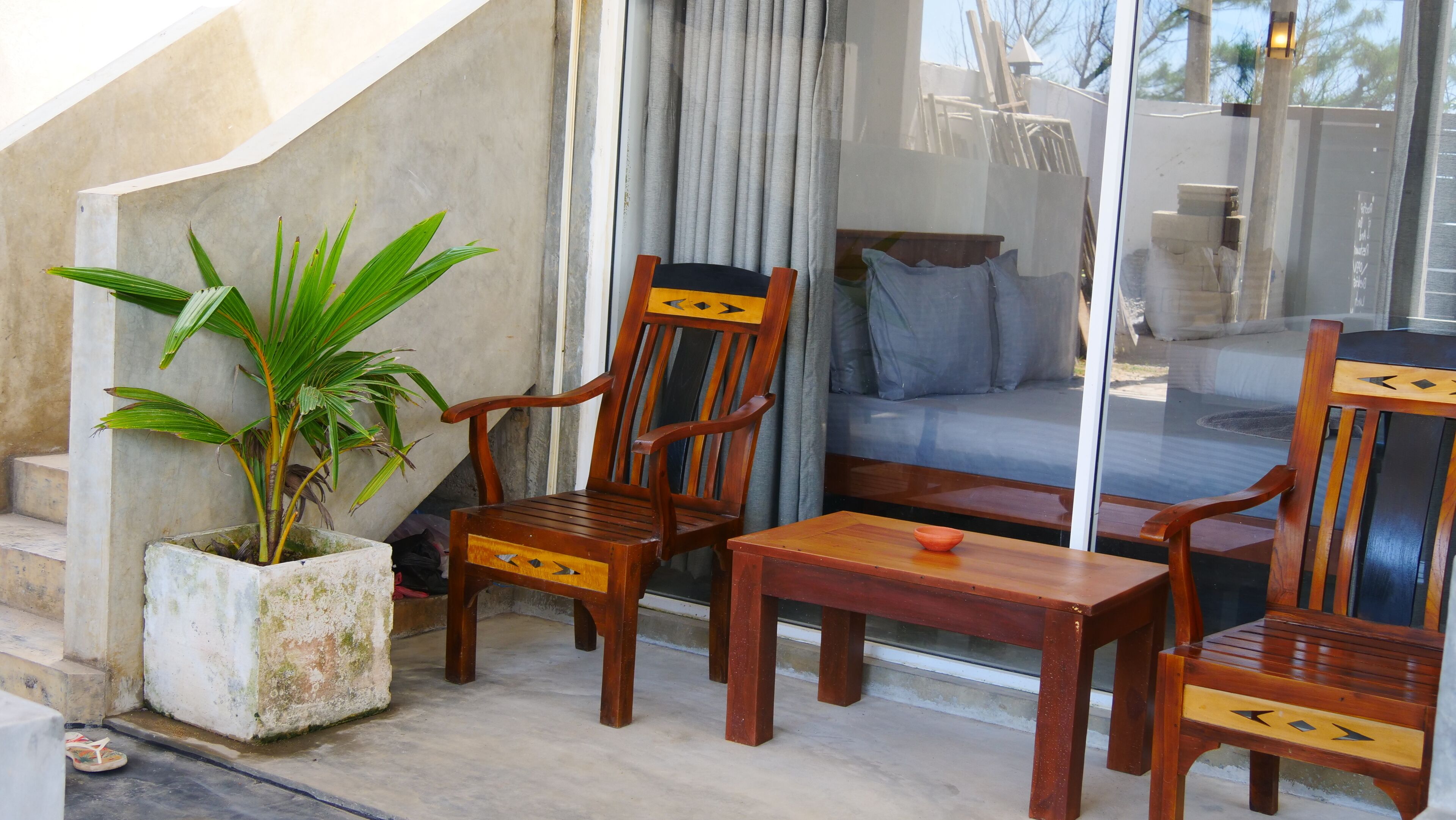 Ein Holztisch und -stuhl auf einem Balkon mit einem Blumentopf.