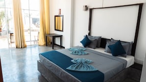 A modern hotel room with a large bed, a desk, and a view of the outdoors. - Cozy Cocos (Weligama)