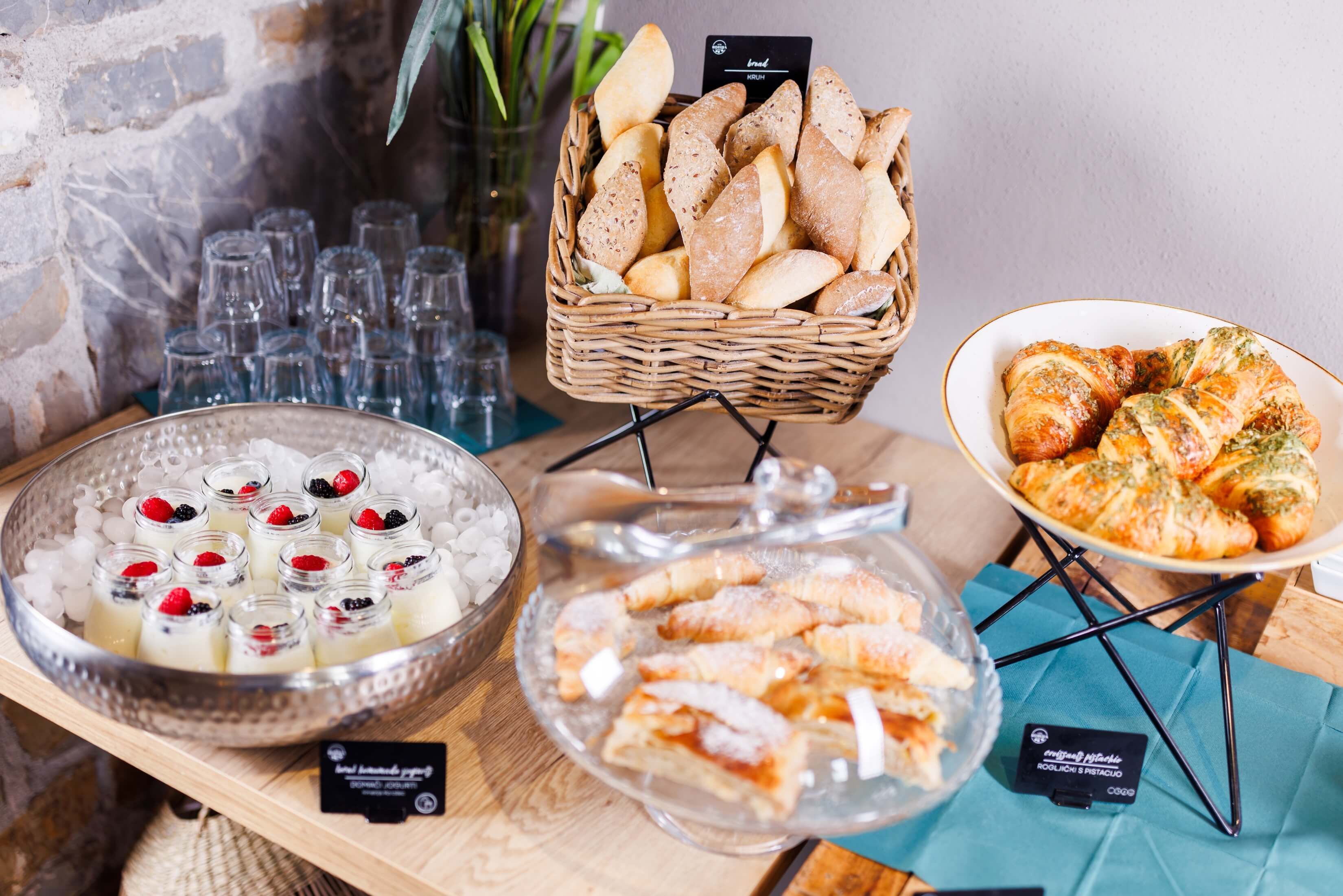 A buffet table with various food items including bread, pastries, and desserts.